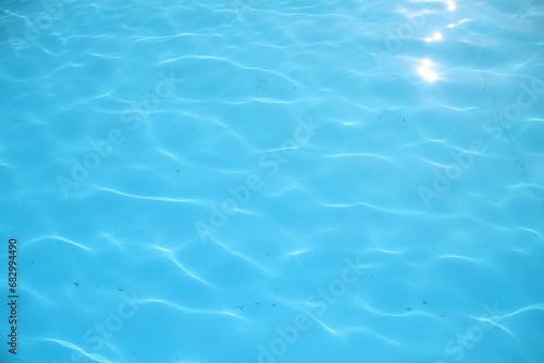 Beautiful in swimming pool. Beautiful blue rippled wave water in swimming pool with sunny reflection background. Texture background of water from a pool.