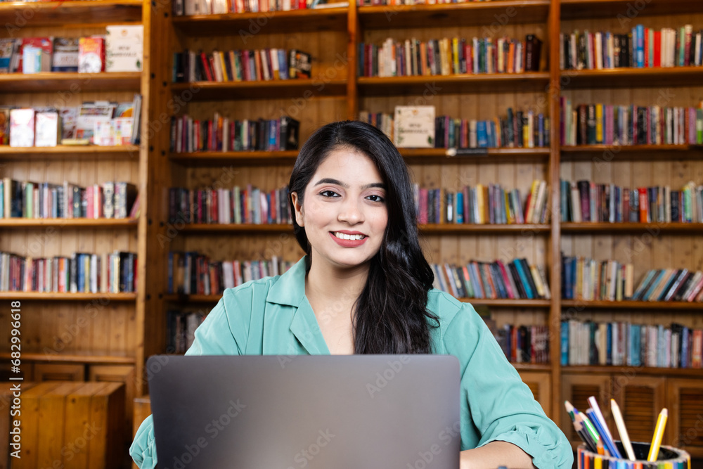 Beautiful young business woman girl student studying or explaining on video call on laptop in school or collage library or working in corporate office searching for information on internet or books Beautiful young business woman girl student studying or explaining on video call on laptop in school or collage library or working in corporate office searching for information on internet or books