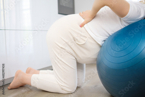 Pregnant woman has pain in the back and doing exercise on the fit ball. photo