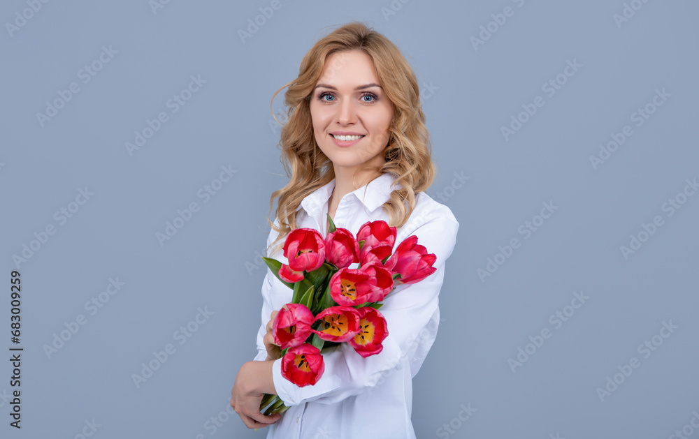 smiling young woman with spring tulip flowers on grey background smiling young woman with spring tulip flowers on grey background