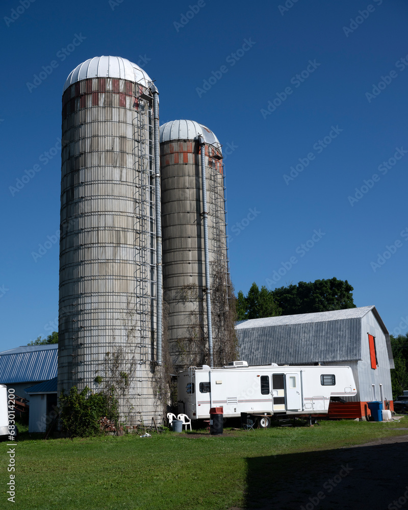 A recreationnal vehicle beside two silos and a barn A recreationnal vehicle beside two silos and a barn