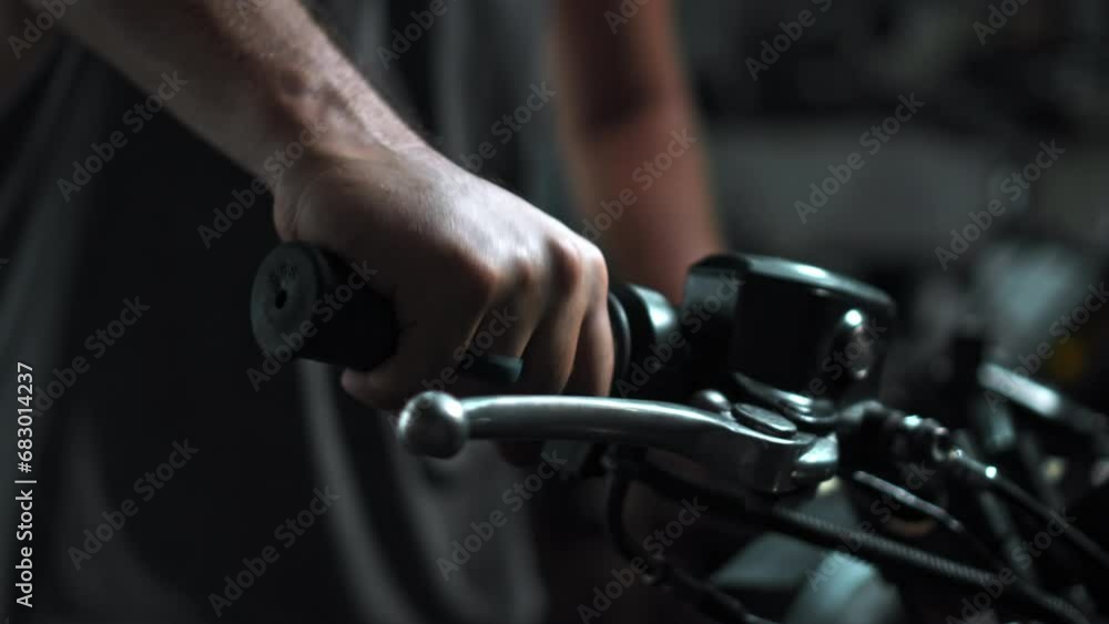 Men's hands start motorcycle in dark workshop holding gas handle Men's hands start motorcycle in dark workshop holding gas handle