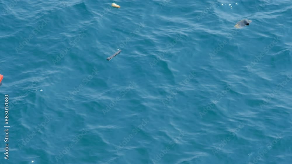 Close up shot of garbage and plastic floating in the ocean and polluting the environment while passing by on the ocean waves Close up shot of garbage and plastic floating in the ocean and polluting the environment while passing by on the ocean waves
