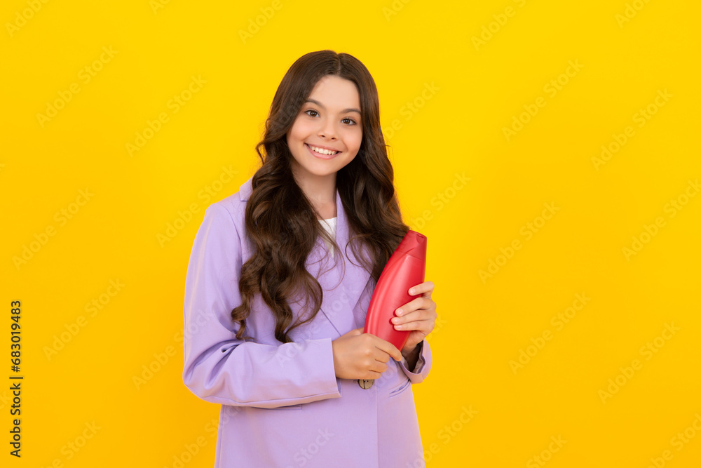 Teen child girl with shampoo bottle or shower gel isolated on yellow background. Kids hair cosmetic product. Happy teenager, positive and smiling emotions of teen girl. Teen child girl with shampoo bottle or shower gel isolated on yellow background. Kids hair cosmetic product. Happy teenager, positive and smiling emotions of teen girl.