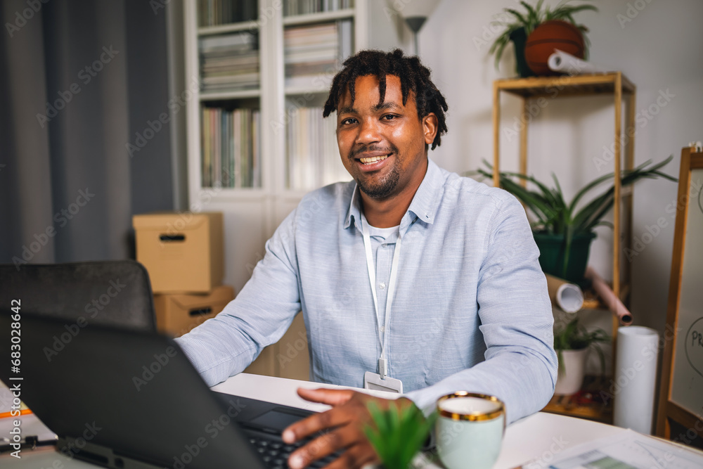 Handsome African American smiling freelancer working remotely from home Handsome African American smiling freelancer working remotely from home