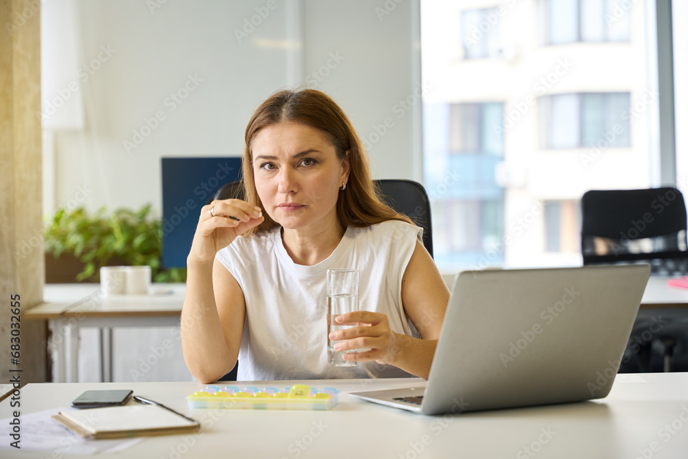 Female manager holds glass of water and tablet in her hands Female manager holds glass of water and tablet in her hands