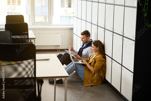 Colleagues with laptops and work documents are located on floor