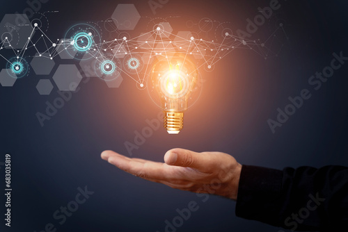 Business idea and financial solution. Light bulb in hand on the background of business skyscrapers. Economy, growth, income concept.