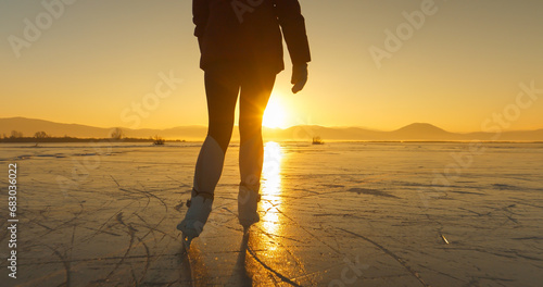 LENS FLARE, SILHOUETTE: A cold winter day with a woman skating in golden light