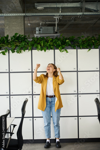 Woman in a yellow jacket rejoices in the office area
