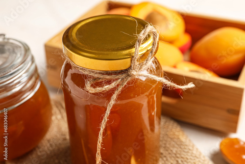 Jar with sweet apricot jam on white background