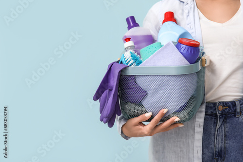 Woman with cleaning supplies on blue background, closeup