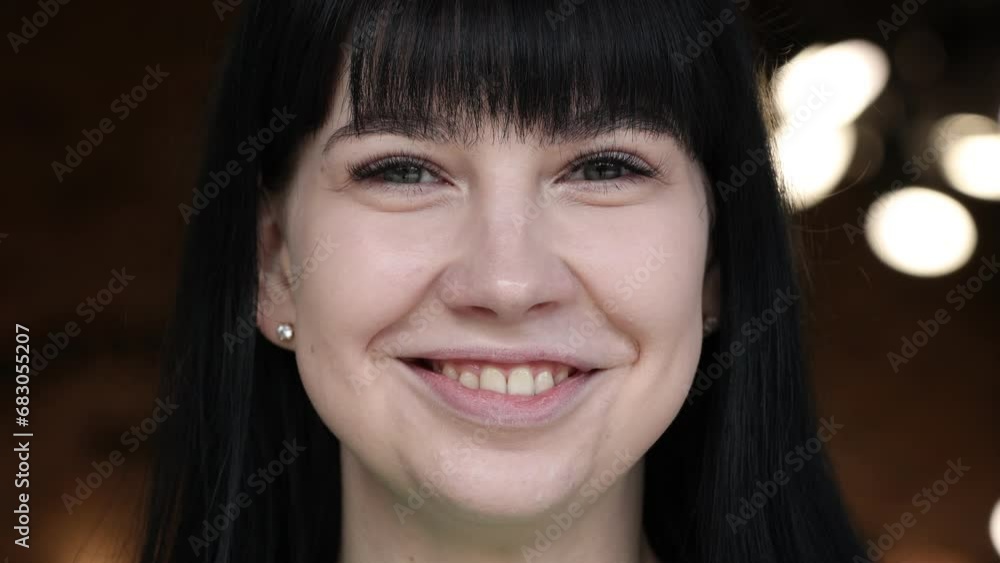 A close up portrait of young beautiful woman with green eyes, smiling looking at camera. beautiful brunette girl with short bang is opening and blinking her eyes. natural beauty.