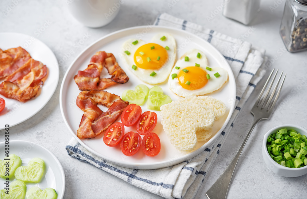 Fresh breakfast with fried eggs, fried bacon slices, bread slices and vegetables in the form of heart for Valentine's day holiday Fresh breakfast with fried eggs, fried bacon slices, bread slices and vegetables in the form of heart for Valentine's day holiday
