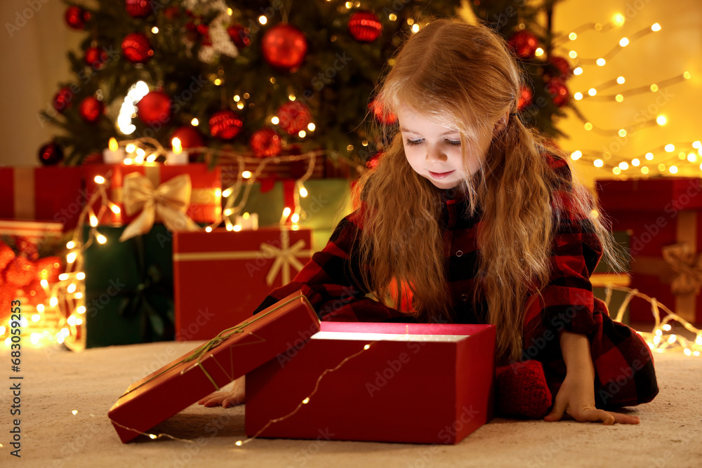 Cute little girl opening Christmas gift at home Cute little girl opening Christmas gift at home