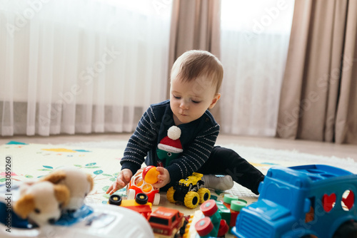 Little boy cute child playful toddler playing different pile colorful toys balls decorated interior cozy atmosphere gifts presents on holiday, educational game for kid