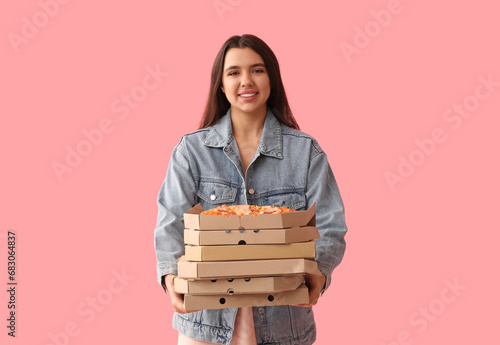 Young woman holding cardboard boxes with tasty pizzas on pink background photo