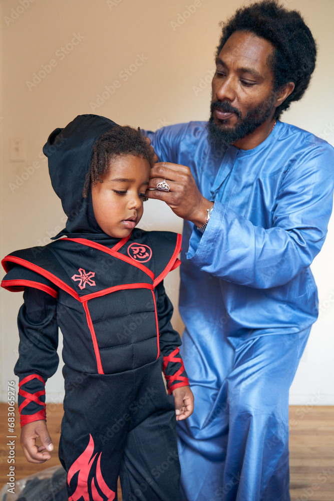 Obraz premium Portrait of Black Father helping Child put on Costume 
