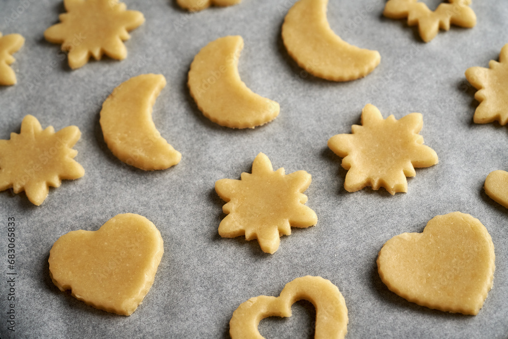 Shapes made of raw pastry dough on baking paper - preparation of Linzer Christmas cookies