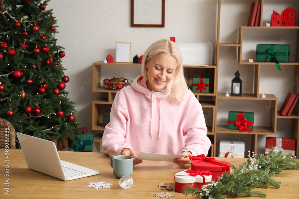 Mature woman with greeting card for Christmas celebration at home Mature woman with greeting card for Christmas celebration at home