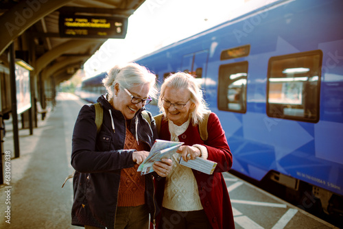 Two senior women at the train station looking at map photo