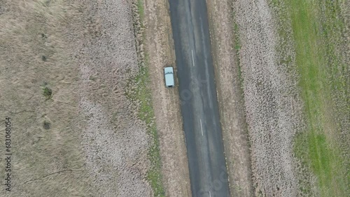 An aerial drone view of a Suzuki Jimny 4x4 driving down a country road in Australia. photo