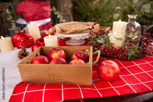 Christmas holiday table with open cranberry, cherry pie on red tablecloth with candles, advent wreath, apples. Flat lay is decorated with green spruce branches, berries of holly, eucalyptus. Homemade