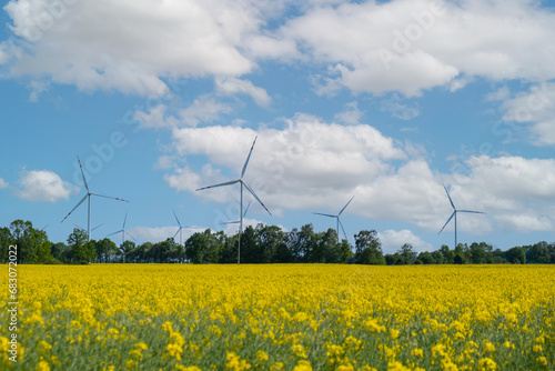 Wind turbine on grassy yellow field against cloudy blue sky in rural area during sunset. Offshore windmill park with stormy clouds in farmland Poland Europe. Wind power plant generating electricity