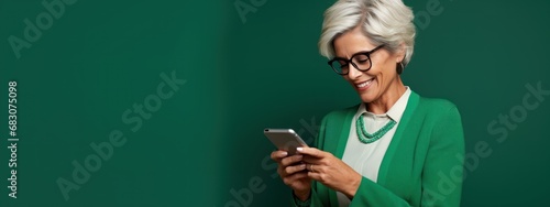 Elderly elegant lady with phone, green background, studio photo