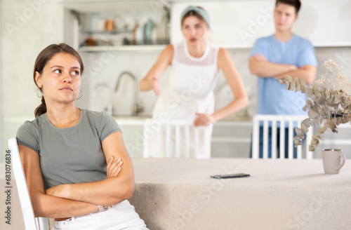 Girl listens to swearing and accusations of inappropriate behavior from mother and brother. Girl indifferently turned away from grumpy mother and older brother, girl neglects swearing and family