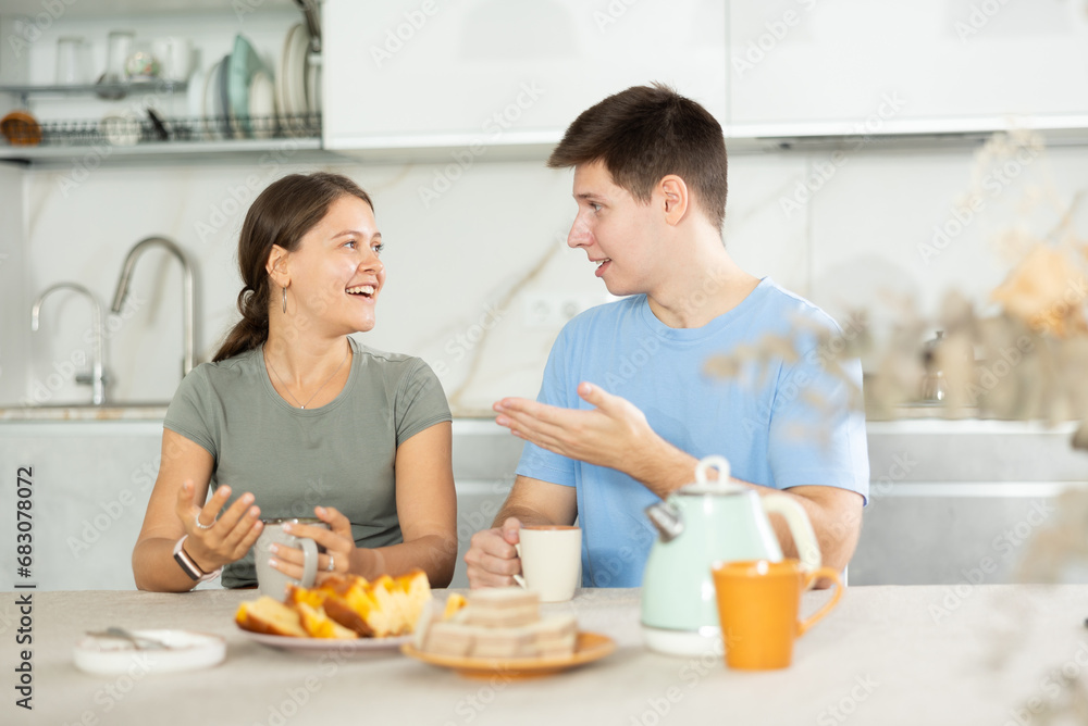 Guy and girl in kitchen talk and laugh during lunch