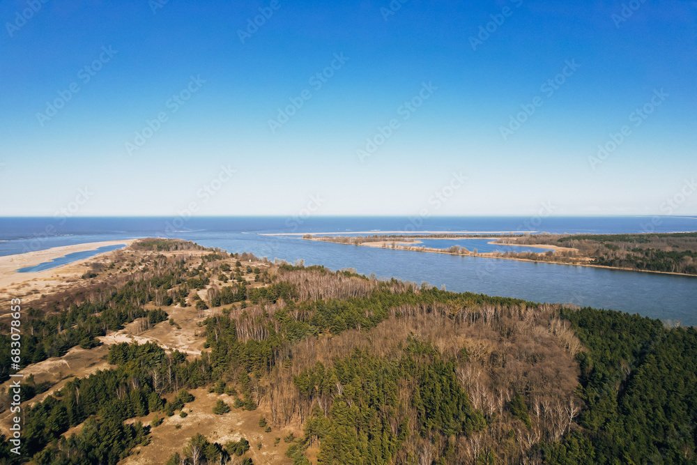 Aerial view drone of river goes into the sea. Delta of Vistula river goes in Baltic Sea in Sobieszewo Gdansk Poland. Forest and small village around river