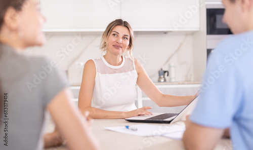 An insurance agent tells a young couple the terms of property and life insurance © JackF