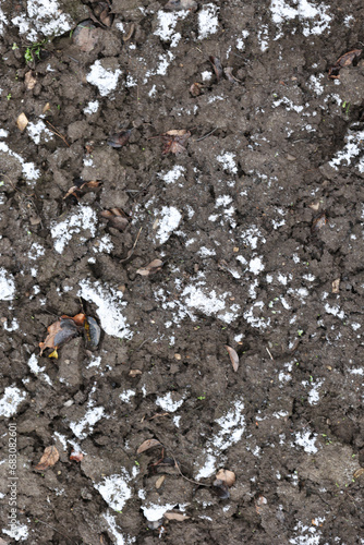 Earth and snow textures. Winter background, the first snow in the field, a small amount of snow. Top view, close-up. It's cold outside