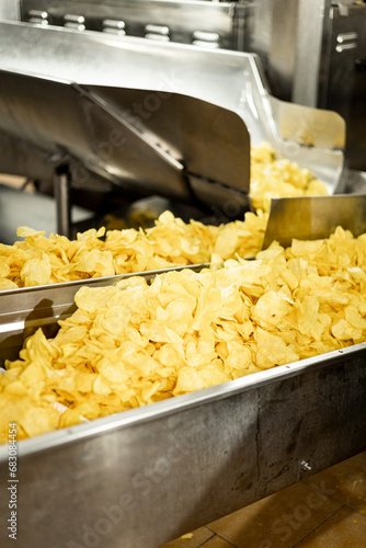 A factory of bagged potato chips. Preparation and manufacturing of potatoes for snacks. Potatoes are transported on a belt for bagging.