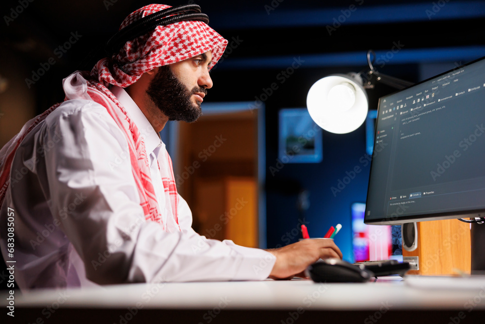 Muslim man types code on a desktop PC. He excels in app programming and ...