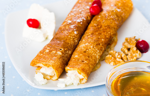 Bulgarian-style crepes Palatschinke with filling of brinsen cheese and walnuts with honey on white dish photo