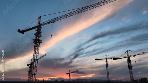 Silhouettes of Construction Cranes Under Colorful Sunset Sky. New Real Estate Development photo