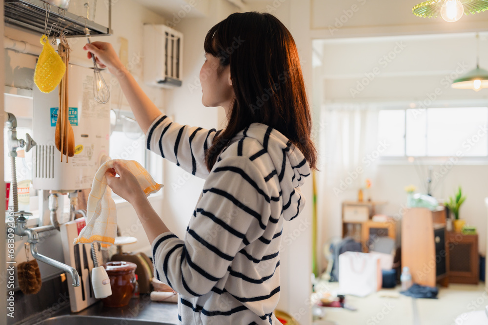団地の台所で家事をする女性