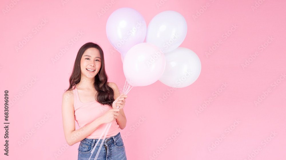 Excited cheerful asian woman holding balloons and hands beside mouth smiling with toothy standing over isolated pink background. Joyful teenager girl with pastel balloons shocked amazed expression. Excited cheerful asian woman holding balloons and hands beside mouth smiling with toothy standing over isolated pink background. Joyful teenager girl with pastel balloons shocked amazed expression.