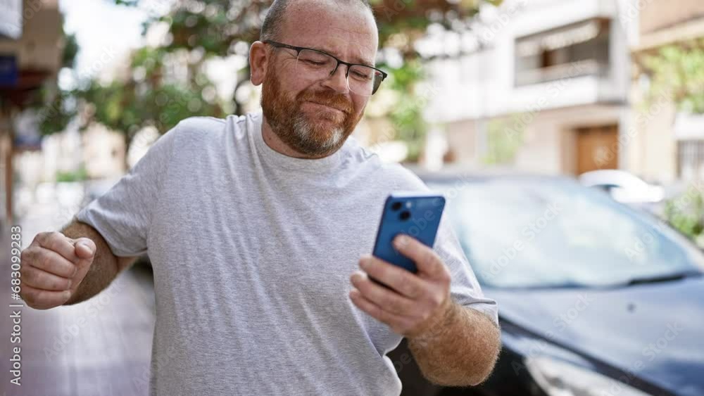 Cheerful, glasses-wearing, bearded, middle-aged caucasian man grooving to music blaring from his phone on a lively, urban street Cheerful, glasses-wearing, bearded, middle-aged caucasian man grooving to music blaring from his phone on a lively, urban street