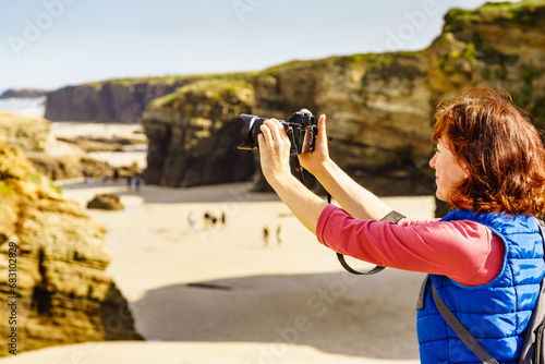 Woman with camera at Cathedral Beach in Spain. photo