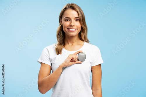 Fotografija Portrait of attractive woman in white t shirt holding pacemaker in hand, looking