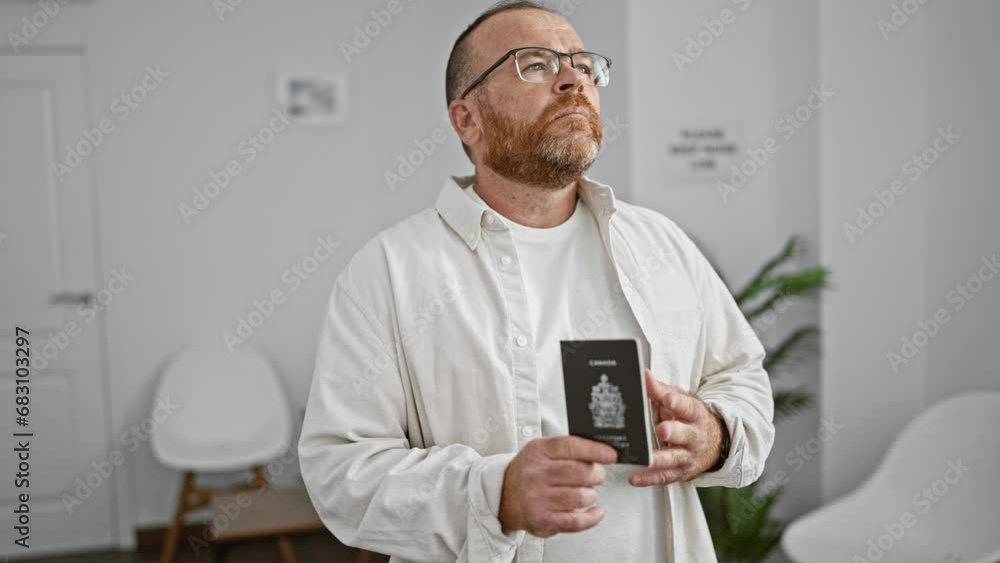 Handsome middle-aged caucasian man, with a beard and glasses, holds his passport, submerged in thought while standing casually in the waiting room, pondering his upcoming travel plans. Handsome middle-aged caucasian man, with a beard and glasses, holds his passport, submerged in thought while standing casually in the waiting room, pondering his upcoming travel plans.