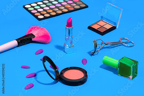 Beauty products makeup brush, lipstick, and nail polish on blue background photo