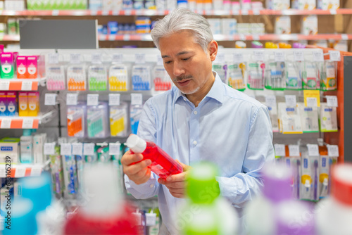 Man with white hair checking product in pharmacy store