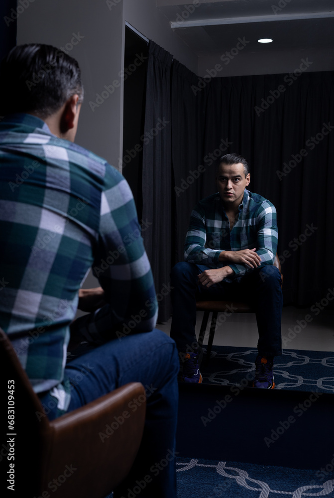 Mexican white man sitting in front of a mirror wearing plaid shirt