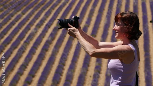 Mature tourist woman against blurred lavender field taking travel photo. Provence in France.