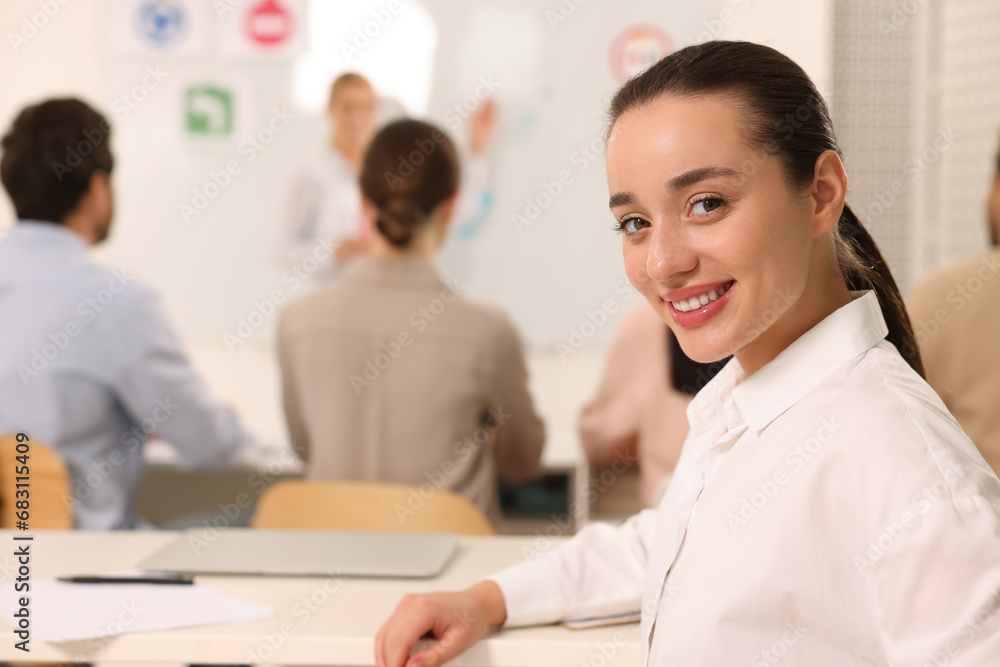 Happy woman at desk in class during lesson in driving school. Space for text Happy woman at desk in class during lesson in driving school. Space for text