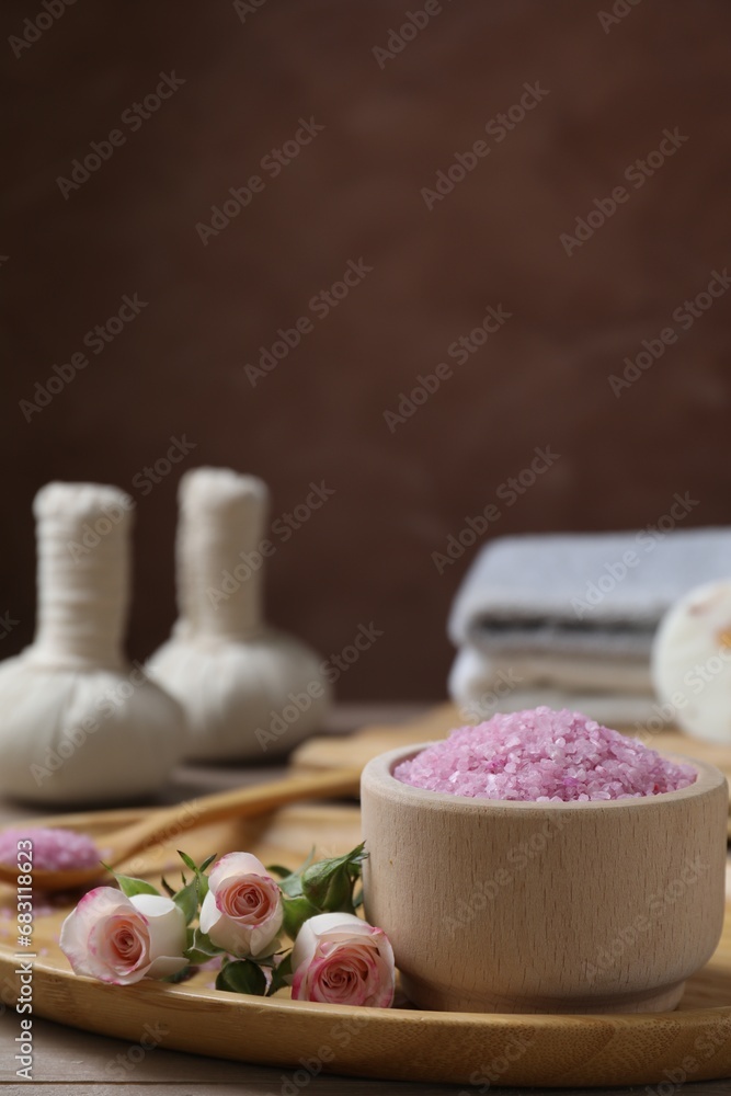 Bowl of pink sea salt and roses on wooden table. Space for text Bowl of pink sea salt and roses on wooden table. Space for text